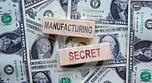 Concept words `manufacturing secret` on wooden blocks on a beautiful background from dollar bills. Business concept