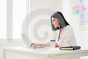 Young asian business woman working on computer laptop in office room with paperwork document