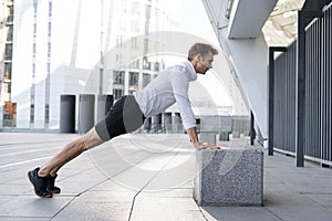 Sportive man training outdoors, doing push ups from box