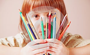 Concept: World of color. Humorous photo of great artist. Portrait of cute little child girl with colored pencils