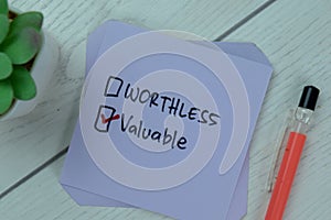 Concept of Worthless or Valuable? Valuable write on sticky notes isolated on Wooden Table