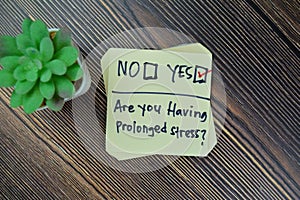 Concept of Are you having prolonged stress? Yes write on sticky notes isolated on Wooden Table