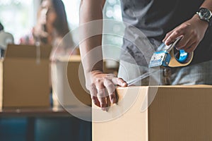 Close-up hand of woman use tape sealing cardboard box