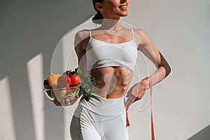Conception of diet. With vegetalbes and fruits. Young caucasian woman with slim body shape is indoors in the studio photo