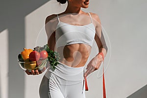 Conception of diet. With vegetalbes and fruits. Young caucasian woman with slim body shape is indoors in the studio photo