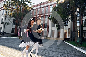 Conception of friendship. Two schoolgirls is outside together near school building