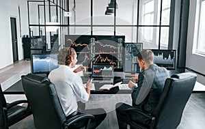 Conception of teamwork. Team of stockbrokers works in modern office with many display screens