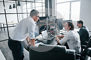 Conception of teamwork. Team of stockbrokers works in modern office with many display screens