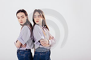 Conception of two offended family members. Two sisters twins standing and posing in the studio with white background