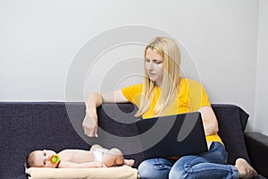 Concepts of Home Working. Portrait of Young Caucasian Mother WIth Baby Boy Working Remotely Using Laptop