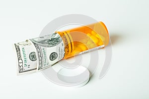 Concepts Money and Prescription Drugs in a container with a hundred dollar bill