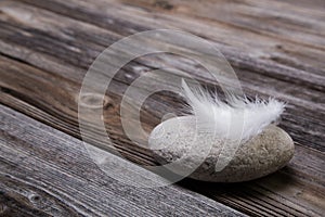 Concepts: Natural wooden background with stone and white feather