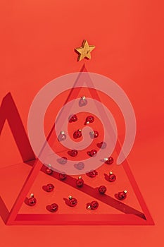 Conceptual Christmas tree with a triangle frame and Christmas balls on red background