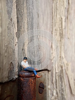 Conceptual Close Up Photo, Gadget Addicted young Man, Holding Smartphone, sitting at corrosive door hinge, under barbed wire