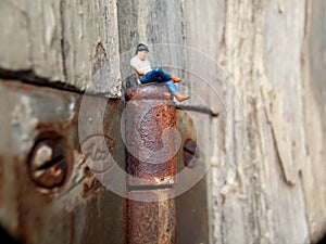 Conceptual Close Up Photo, Gadget Addicted young Man, Holding Smartphone, sitting at corrosive door hinge, under barbed wire