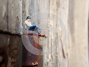 Conceptual Close Up Photo, Gadget Addicted young Man, Holding Smartphone, sitting at corrosive door hinge, under barbed wire