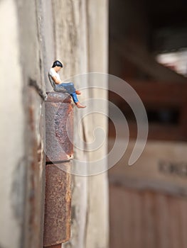 Conceptual Close Up Photo, Gagdet Addicted young Man, Holding Smartphone, sitting at corrosive door hinge, under barbed wire