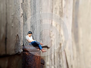 Conceptual Close Up Photo, Gagdet Addicted young Man, Holding Smartphone, sitting at corrosive door hinge, under barbed wire