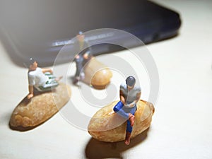 Conceptual Close Up Photo, Two Man Chit Chat and one other sit at peeled peanut enjoy with his smartphone in the afternoon, illust