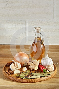 Conceptual composition of different spices and oil bottle on a wooden tray on rustic table, closeup, selective focus.