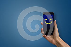 Conceptual the customer responded to the digital survey. The client showing mobile phone screen with happy face. Depicts that