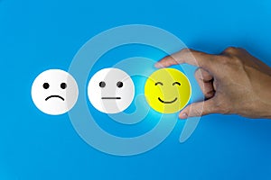 Conceptual the customer responded to the survey. The client using hand choose happy face smile icon on blue background.Depicts