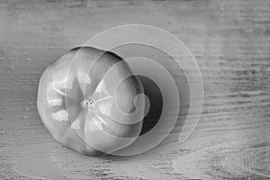 Conceptual decoration of a cafe: white painted tomato on wooden background. Black and white vintage color designed