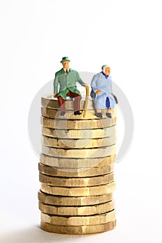 miniture figure retired couple sat on a stack of pound coins photo