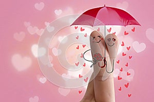 Conceptual finger art. Lovers are embracing and holding umbrella with falling hearts. Stock Image