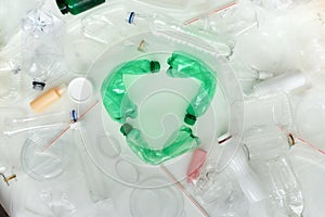 Conceptual flatlay with different used containers and recycle symbol made of green plastic bottles in the center