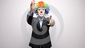 Conceptual footage of clown in business suit making shot signs from hands
