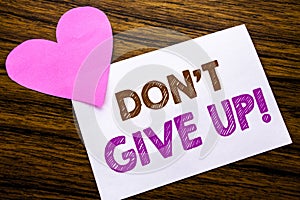 Conceptual hand writing text showing Don t Give Up. Concept for Motivation Determination, written on sticky note paper, wooden woo