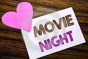 Conceptual hand writing text showing Movie Night. Concept for Wathing Movies written on sticky note paper, wooden wood background