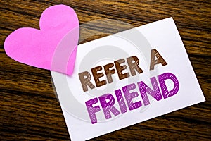 Conceptual hand writing text showing Refer A Friend. Concept for Referral Marketing written on sticky note paper, wooden wood back