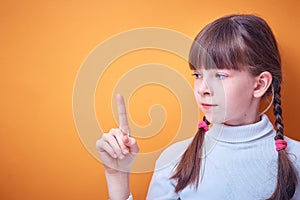 Conceptual idea, Caucasian teen girl shows index finger up on colored background, place for text