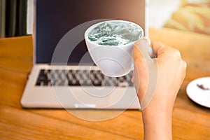 Conceptual ideal hand holding cup of coffee with ocean wave and