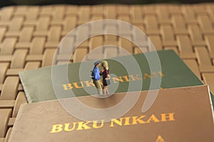 Conceptual illustration photo for Lovely moment, Young Couple Mini figure Toy kissing beyond Buku Nikah, or Indonesia Wedding