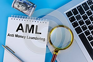 Conceptual image of business acronym AML Anti Money Laundering, written in a notebook lying on a table with a laptop