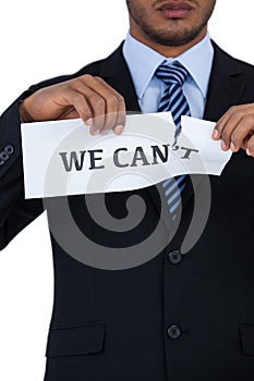 Conceptual image of businessman tearing a paper that reads we cant