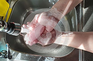 Conceptual image of cleanliness and hygiene by washing hands with soap and water over running tap.