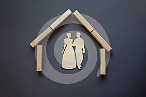 Conceptual image of family values and adoption. House from wooden blocks on beautiful grey background. Family sign