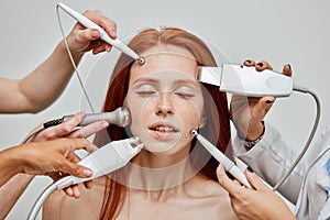 Conceptual image of female emotional face and cosmetologist hands with devices