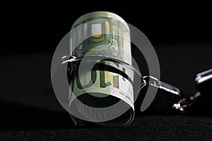 Conceptual image of financial dependence, bundle of money is bound by one side of handcuffs.