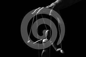 Conceptual image of a hand with strings to control a marionette in monochrome