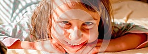 Conceptual image: happiness and a sense of absolute safety. Young child girl wake up and smiling in sun rays