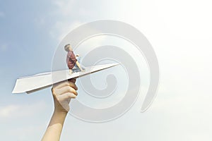 Conceptual image of a little boy who dreams of flying on a paper airplane in the sky