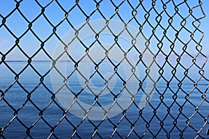 Conceptual image of longed-for freedom seen with metal fencing breaking free on side to open waters beyond