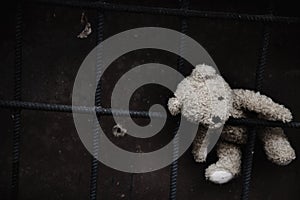 Conceptual image: lost childhood, loneliness, pain and depression. Dirty toy Teddy bear lying down outdoors. Copy space