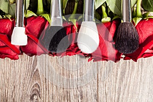 Conceptual image of make-up brushes next to roses