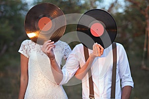 Conceptual Image of Man And Woman Hold A Vinyl Record Discs On Their Faces